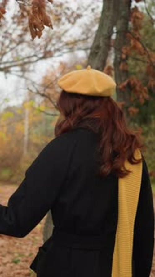Excited Lady in Yellow Beret Touching Autumn Foliage in Forest