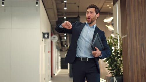 Smiling Businessman Waving Hello in Modern Office