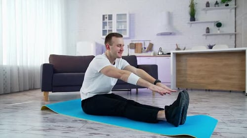 Man Stretching on Yoga Mat in Modern Home