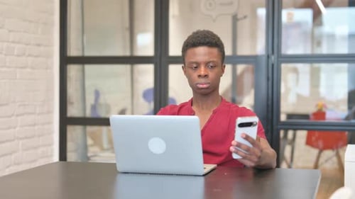 Young Adult Working at Desk with Laptop and Phone