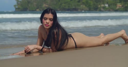 Una chica latina se pone un bikini tipo tanga mientras disfruta de la playa de arena blanca en el entorno caribeño de Trinidad