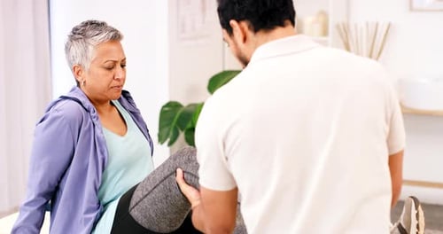 Leg pain, physiotherapy and mature woman with chiropractor for knee injury in a professional office