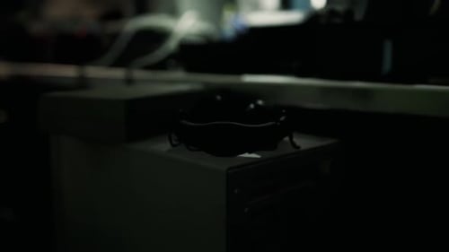 Un objeto circular negro se coloca sobre una mesa lisa en medio de un entorno con poca luz