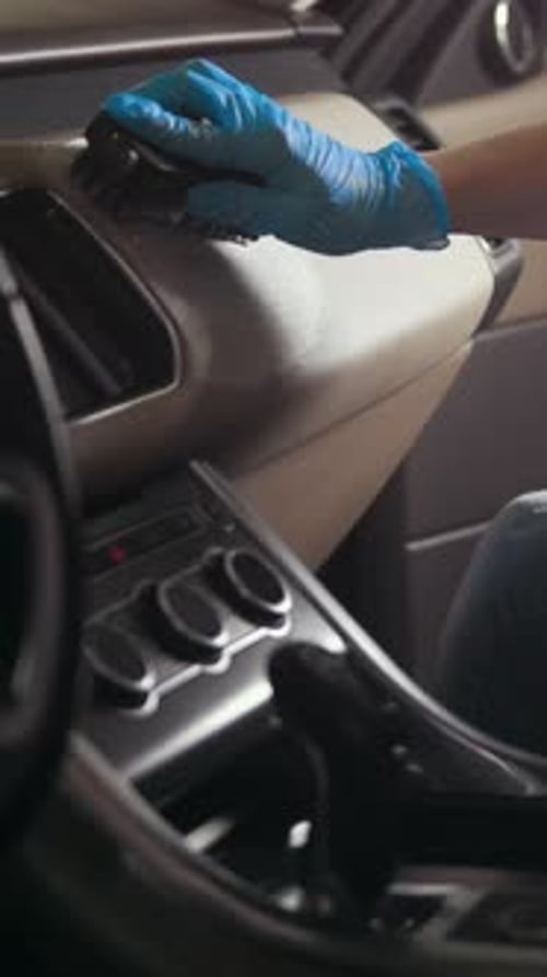 Detailer Cleaning Interior of Vehicle with Glove and Brush
