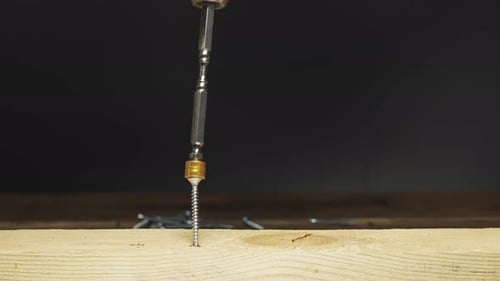 screwing a self-tapping screw into a wooden board with a screwdriver with a magnetic head, slide, cl