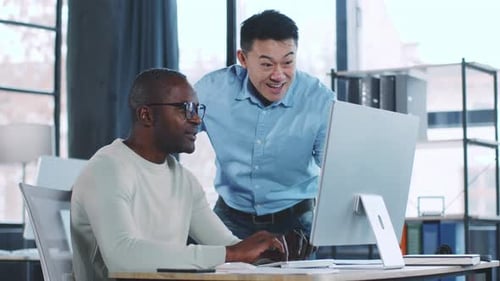 Two Colleagues Working Together on a Computer in a Modern Office Setting During the Day