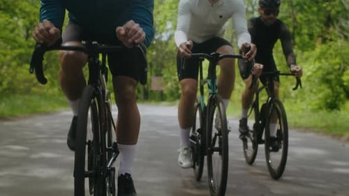 Radfahrer in Trainingsanzügen fahren schnell Fahrrad auf der Landstraße