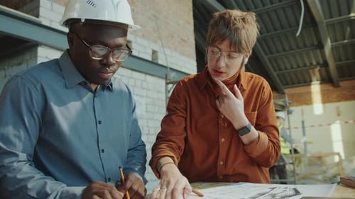 Woman Discussing Floor Plan with Building Contractor on Site