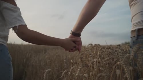 Un angle moyen-bas révèle les mains filmées d'un couple métisse se tenant la main alors qu'il marche de façon romantique