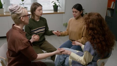 Four Women Sitting in Circle and Holding Hands During Supportive Group Session