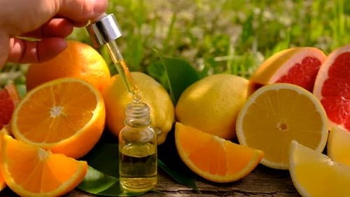 Hand Extracting Liquid from Bottle with Citrus Fruits