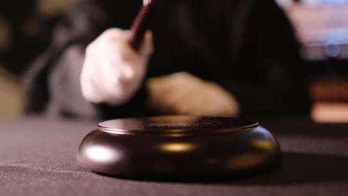 Un juez que golpea un mazo simboliza la toma de decisiones cruciales y la autoridad dentro de la sala del tribunal
