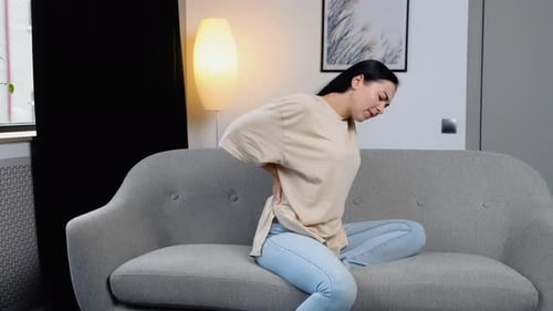 Woman Experiences Lower Back Pain on Couch
