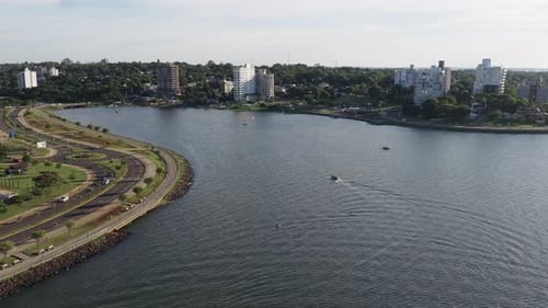 Drone orbit of Posadas waterfront showing Bahía El Brete, curved road and modern buildings skyline