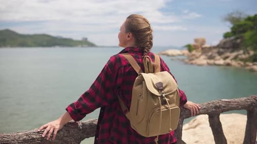 Woman with Backpack Looking Out At Ocean