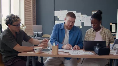 Black Female UI Designer Discussing App Mockups with Male Colleagues at Office