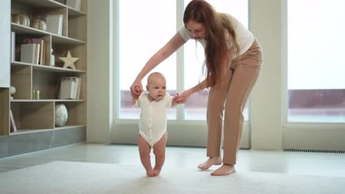 Baby Development First Steps Little Infant Girl Making First Steps at Home Happy Mother Supporting