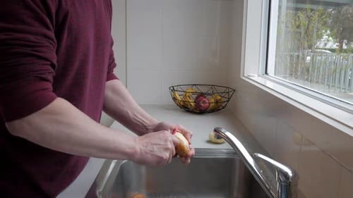 Man Peels Potato in Bright Kitchen
