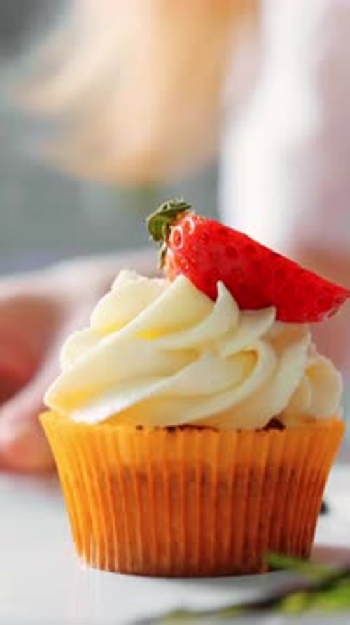 Cupcake Being Decorated With Strawberry and Rosemary