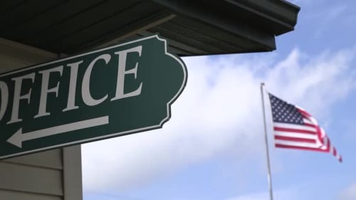 A green "office" sign with am American flag in the background.
