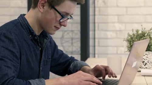 Focused Man Types on Laptop in Bright Room