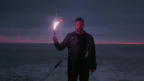 Man Holds Torch on Pier at Dusk