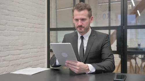 Frustrated Businessman Using Tablet in Modern Workplace