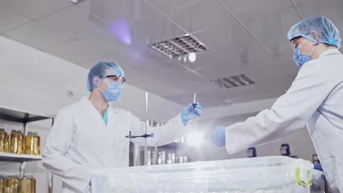 Workers in the Laboratory Area Pack the Chemical Fluid Into Small Jars with Pipettes