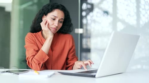 Thoughtful Woman Working on Laptop in Modern Office