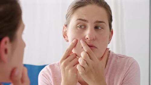Woman examining face in mirror