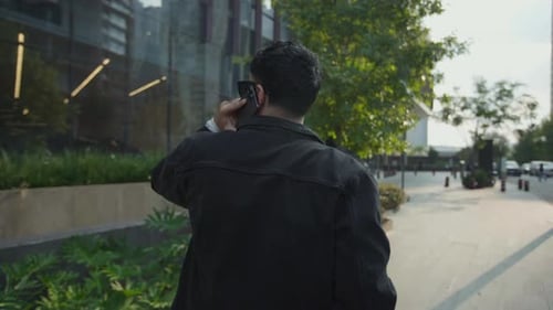 Latin Male Traveler Walking Away Continuously Talking on Mobile Phone