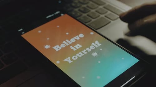 Inscripción «Cree en ti mismo» en la pantalla del teléfono móvil Los rayos de luz provienen de la pantalla de la mano masculina