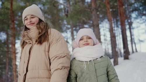 Happy Sisters Enjoying a Snowy Winter Day in the Forest