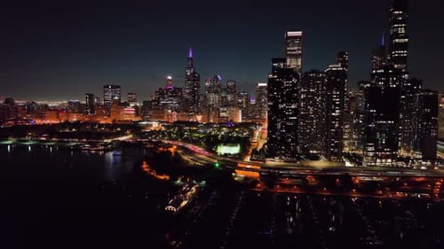 Volando sobre el puerto de DuSable, hacia el Parque del Milenio, en la iluminada Chicago, EE. UU. - Aerial vi