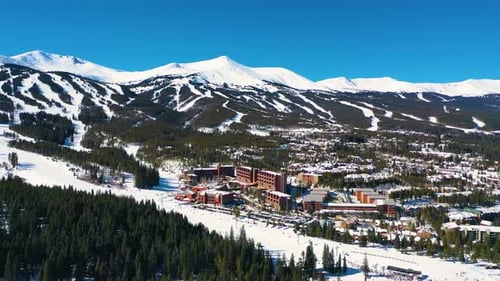 Ski Resort with Slopes and Trails on top of Beautiful Mountains Covered in White Powder Snow. Aerial