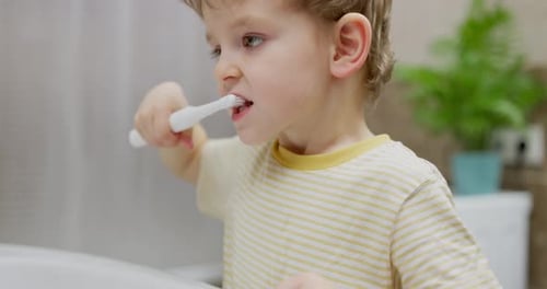 Child Brushing Teeth in Bright Bathroom