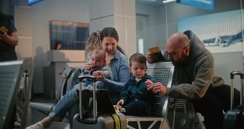 Family with Kids Waiting for Airplane Flight in Crowded Airport Terminal