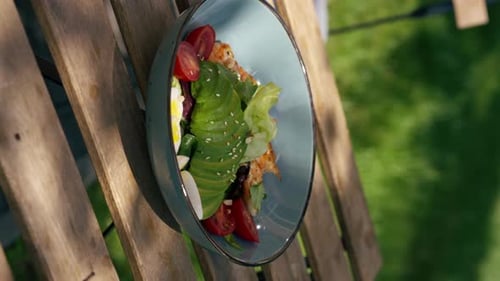 Close Up in a Restaurant on the Street on Plank Table a Blue Plate with a Warm Salad with Avocado