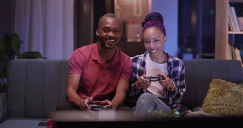 Couple plays video games together on couch at home