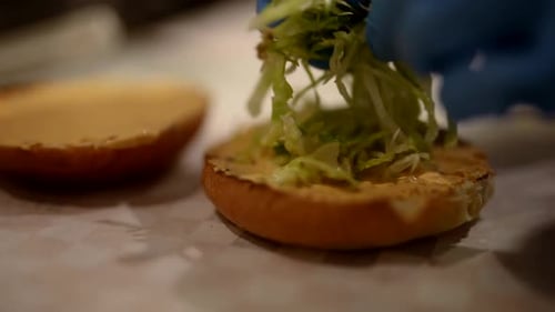 Closeup View of Cooking Classic Hamburger with Fresh Salad in Kitchen of Fast Food Restaurant