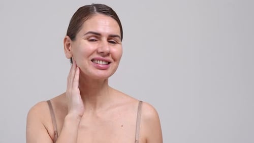 Woman Touching Her Face Smiling in Studio