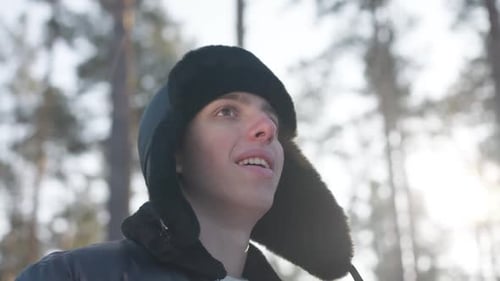 Excited Carefree Young Man Looking Away Smiling Standing in Sunlight in Winter Forest