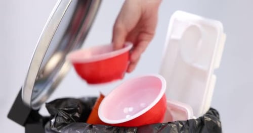 Tossing plastic waste into trash can for recycling