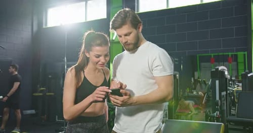 Waist Up Portrait View of the Calm Sports Girl Looking Something at the Smartphone Screen with Her