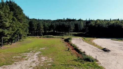 Ascending aerial view over woodland freestyle dirt trail course rising above trees