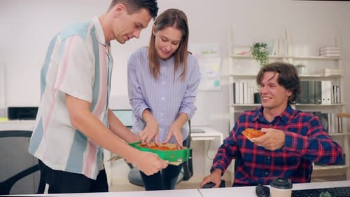Group of businessman and woman eat pizza while working in the office.