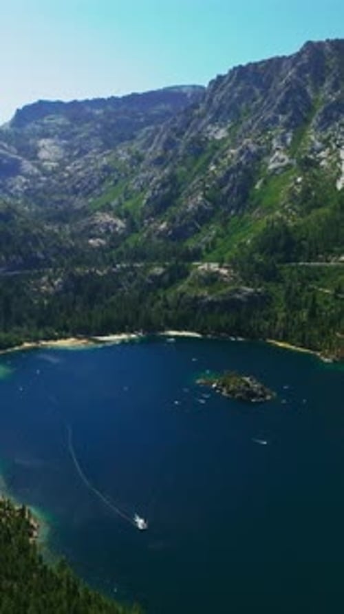 Boats sailing by the blue lake with tiny island in the middle.