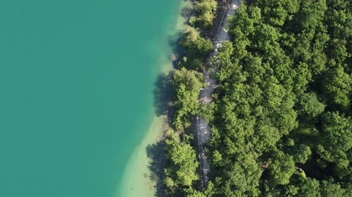 Top view of a lake surrounded by lush greenery. Drone footage of peaceful and picturesque lake scene