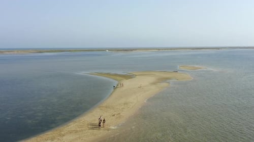 People walking out on strip of sand in the middle of the ocean on warm summers day, portugal