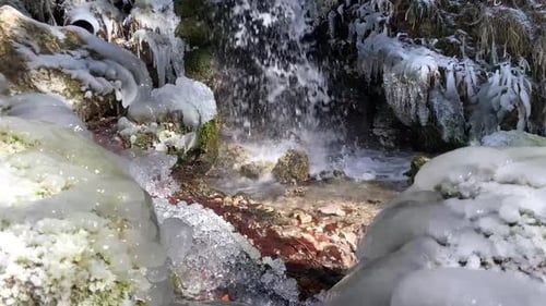 Gefrorener Wasserstrom mit Wasserfall. Gefrorene Pflanzen und Gras rund um einen Fluss im kalten Winter. Wasser f